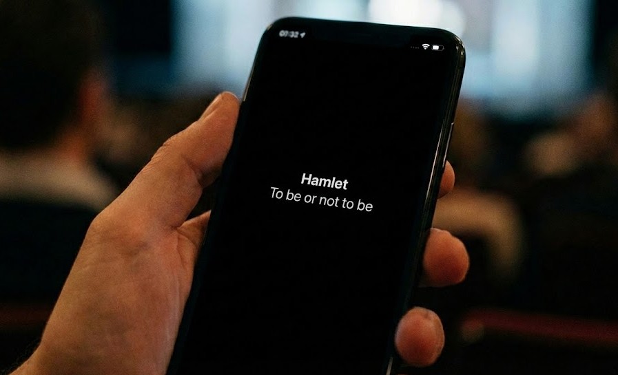Uno spettatore legge i sopratitoli di uno spettacolo sul telefono durante una rappresentazione dal vivo
