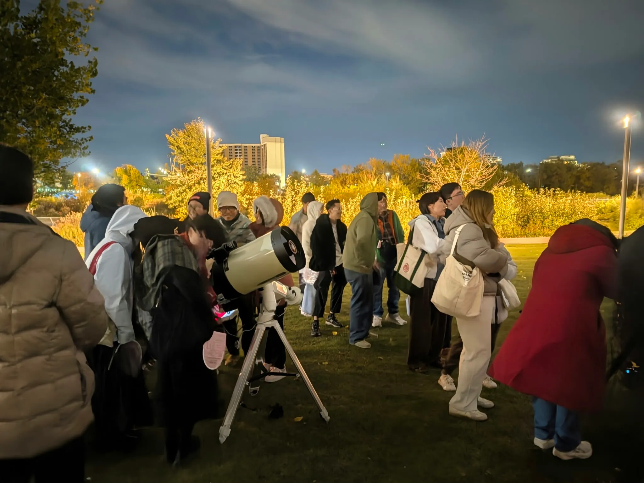 People gather around a telescope under the evening sky in Calgary